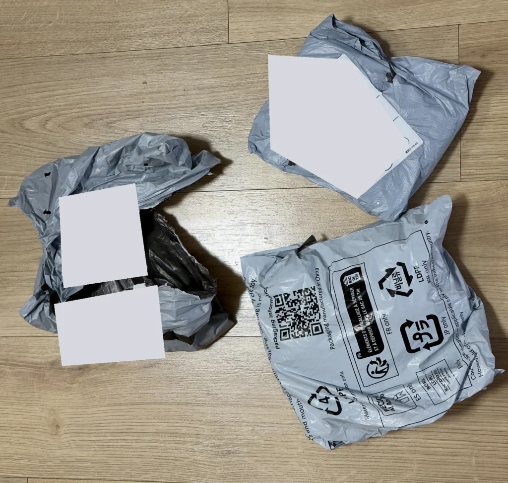 Viacero vnorených obalov zásielky AliExpress po rozbalení so zakrytými údajmi na štítkoch.